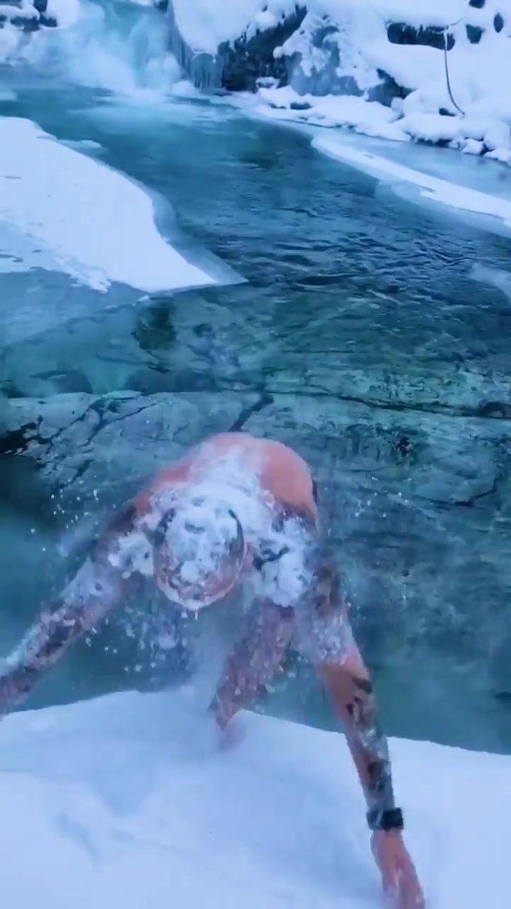 Man Playing in Snow Near Frozen Waterfall